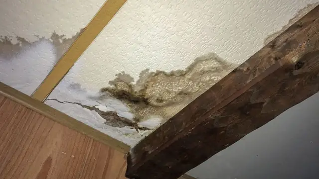 Water-damaged ceiling and wooden beam after an upstairs leak