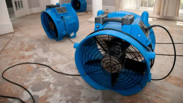 Blue air movers drying a damp floor